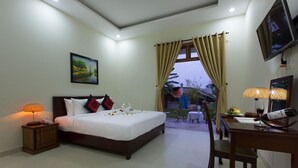 A hotel room with a bed, bedside lamp, TV, and a dining area with a table and chairs. - Herbal Tea Homestay (Da Nang)