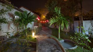 A stone pathway leading to a building with a red roof, surrounded by lush greenery and a small pond. - Herbal Tea Homestay (Da Nang)