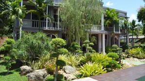A multi-story hotel with a landscaped garden featuring various trees and shrubs. - B Square Hotel (Khanom)