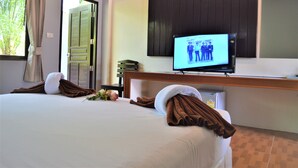 A hotel room with a bed, a television on a stand, a door, and a window with curtains. - B Square Hotel (Khanom)