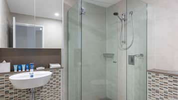 A modern bathroom with a glass-enclosed shower, a white sink, and a tiled backsplash.