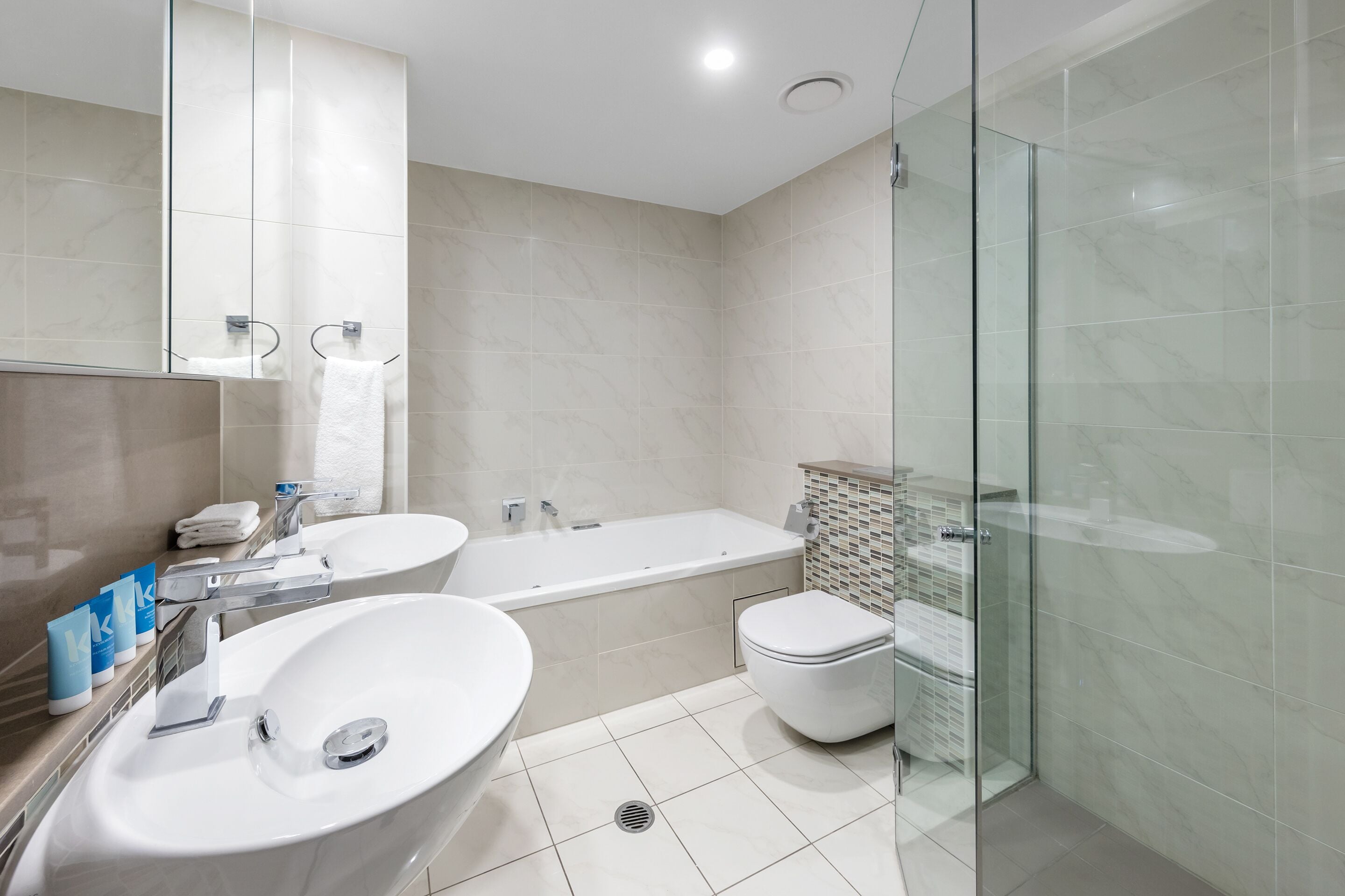 Ein modernes Badezimmer mit einer großen Badewanne, einem separaten Waschbecken und einer gläsernen Duschkabine.