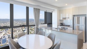 Une cuisine moderne dotée d’un grand îlot central, d’appareils électroménagers en acier inoxydable et offrant une vue sur la ville grâce à de grandes fenêtres.