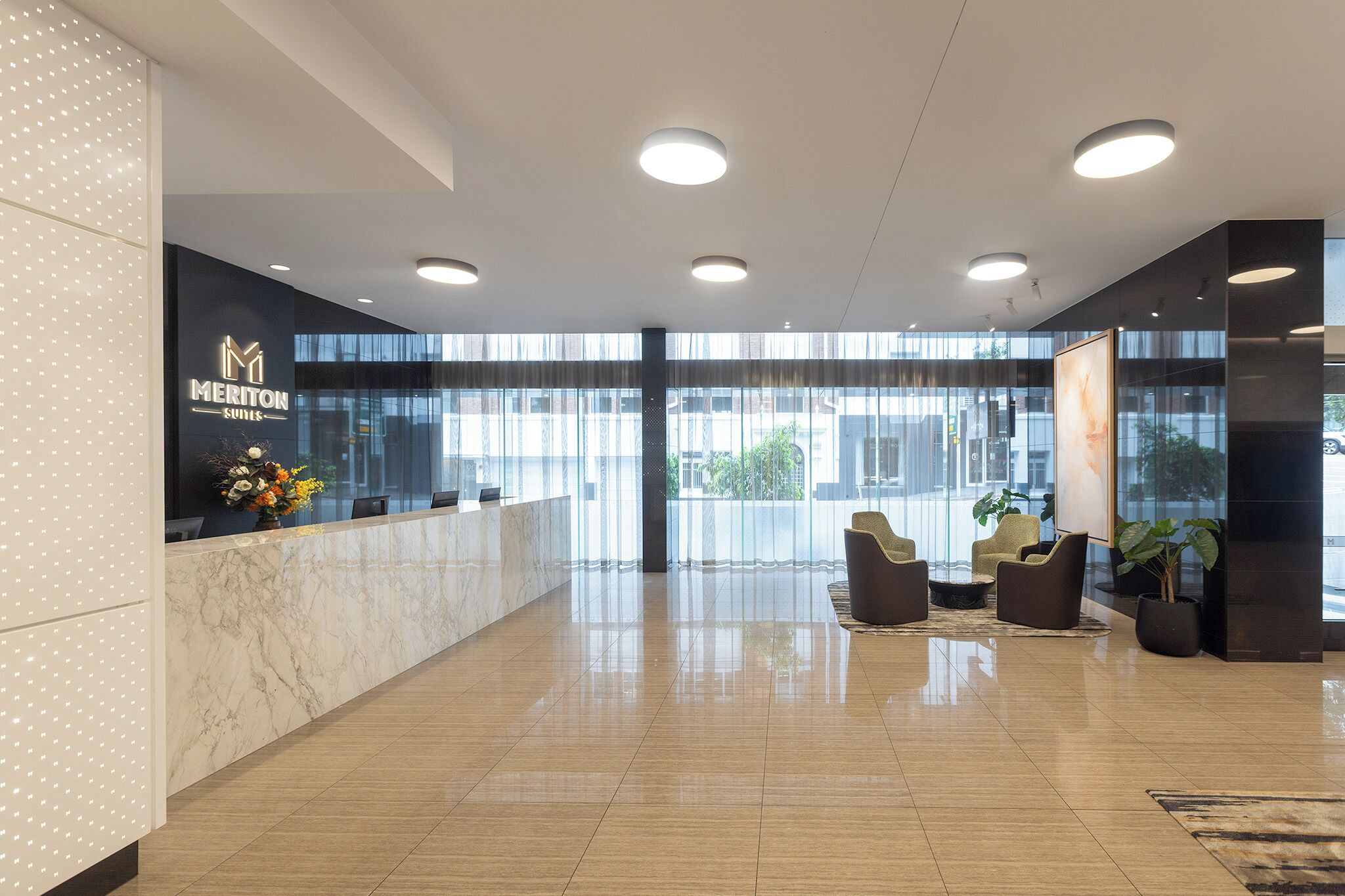 A hotel reception area with a marble counter, modern lighting, and seating.