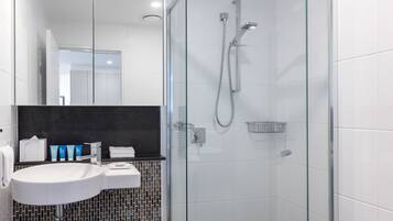 A modern bathroom with a glass-enclosed shower, a white sink, and a tiled backsplash.