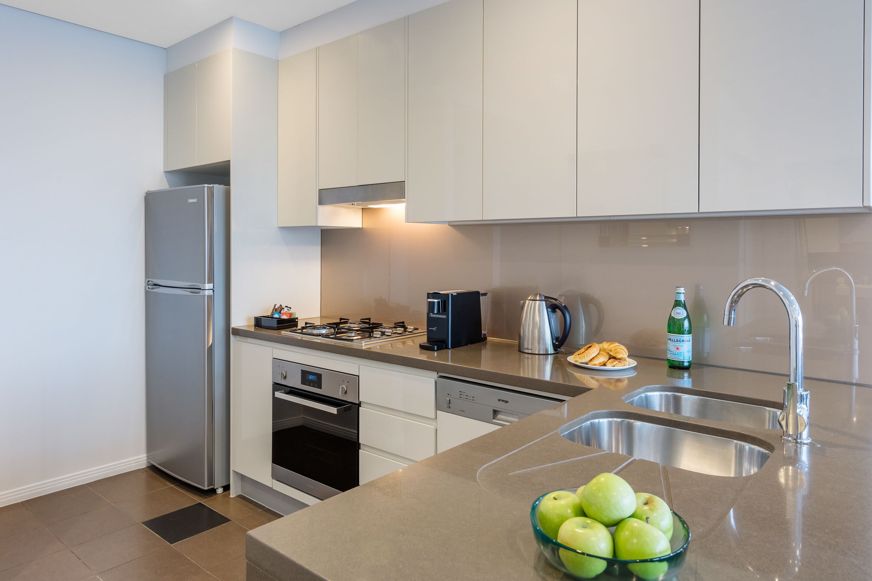 Una cocina moderna con electrodomésticos de acero inoxidable, lavavajillas y un fregadero.