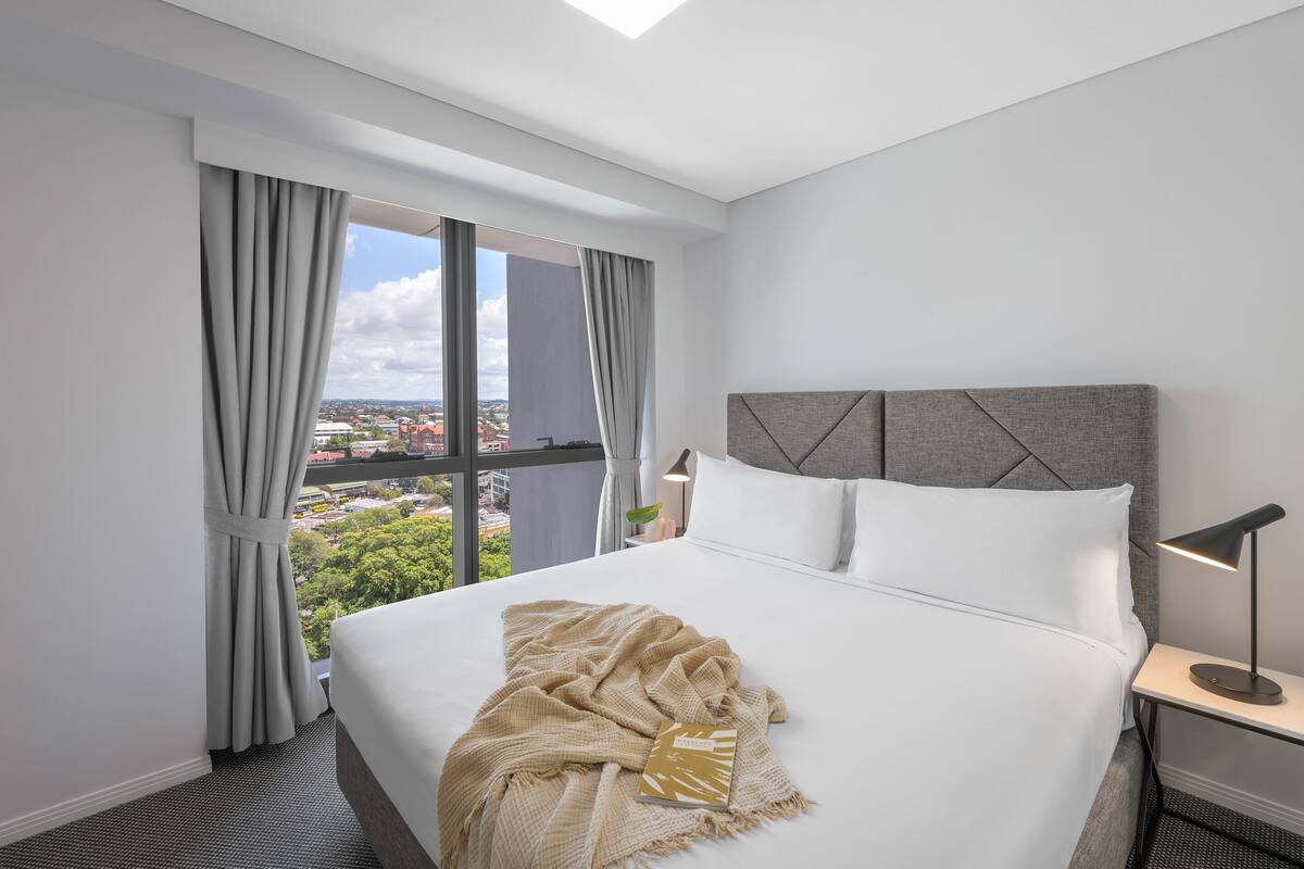Habitación de hotel con una cama grande, vistas a la ciudad y un diseño moderno.