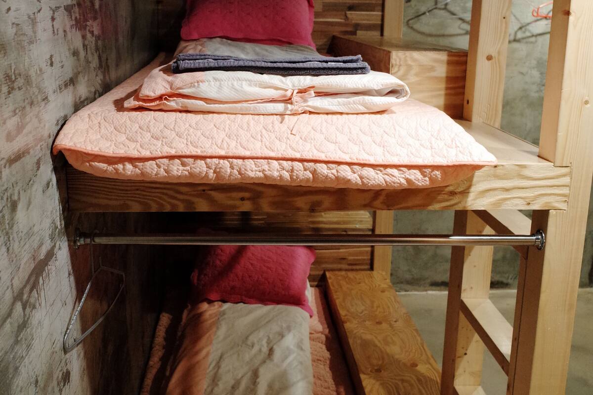 Un lit superposé avec une structure en bois, un matelas et des oreillers.