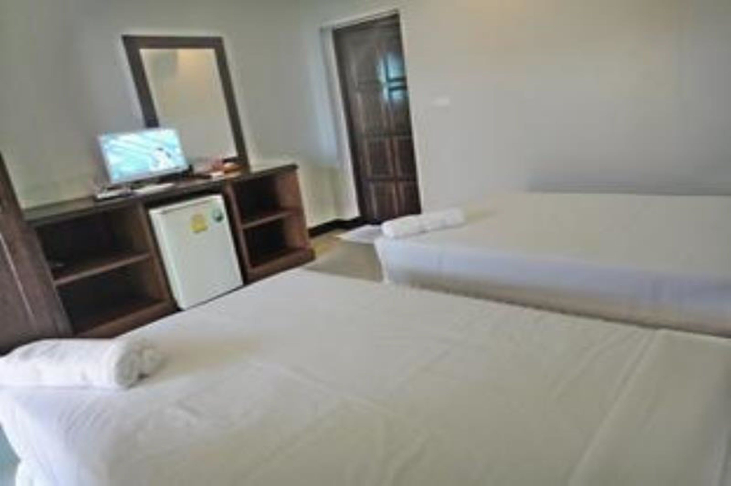 A hotel room with two beds, a small desk with a television, and a wardrobe.