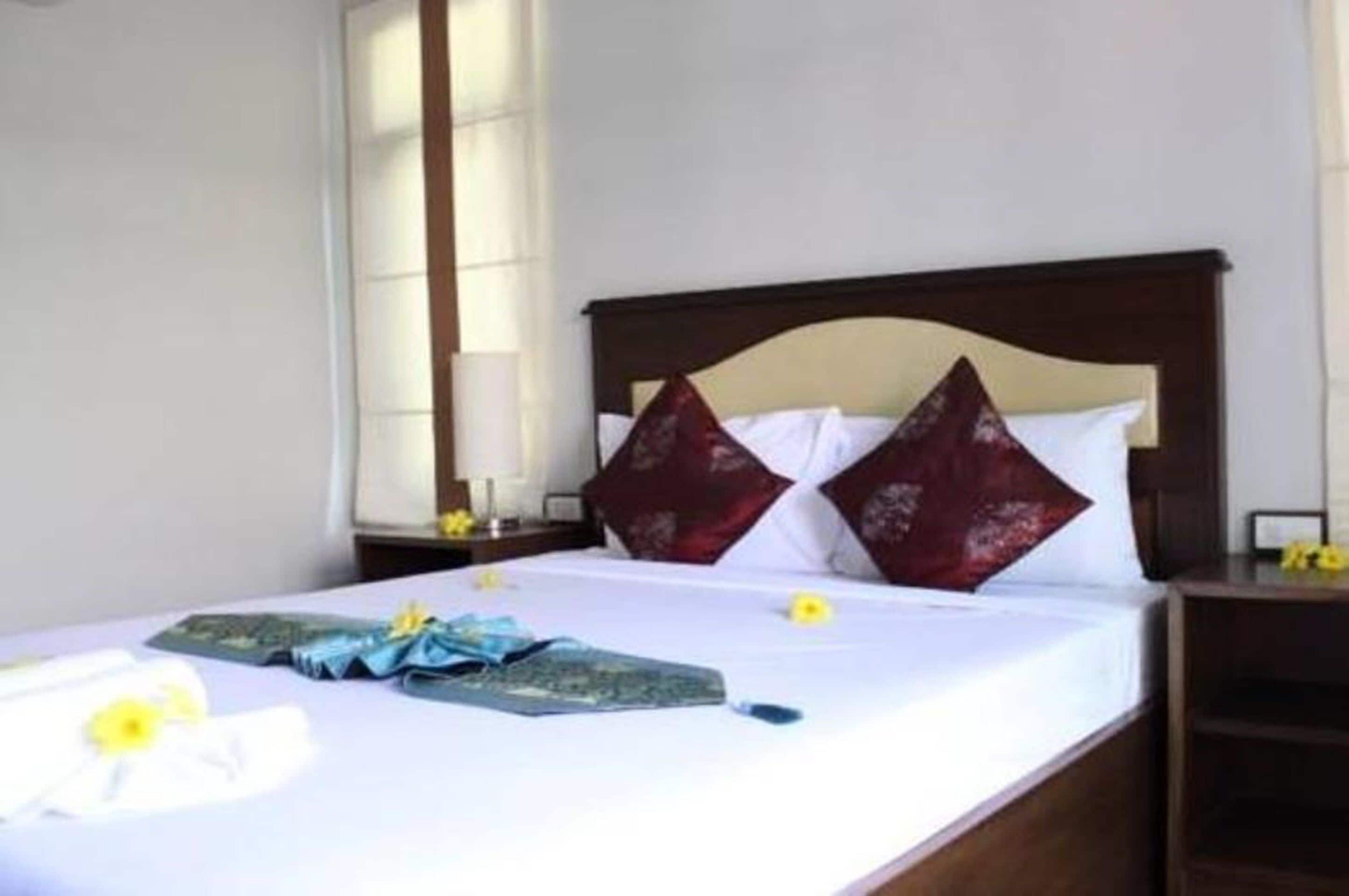 A neatly made bed with a dark headboard, white bedding, and decorative pillows.