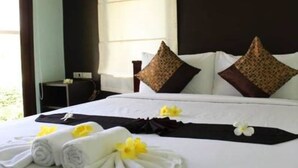 Una habitación de hotel con una cama bien hecha, almohadas y una toalla con un flor.