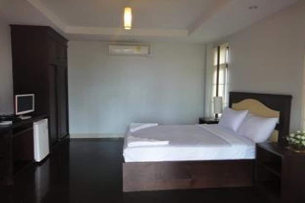 Une chambre d’hôtel avec un lit, un bureau avec un ordinateur et une petite table avec une lampe.