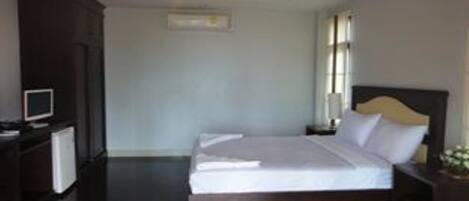 Une chambre d’hôtel avec un lit, un bureau avec un ordinateur et une petite table avec une lampe.