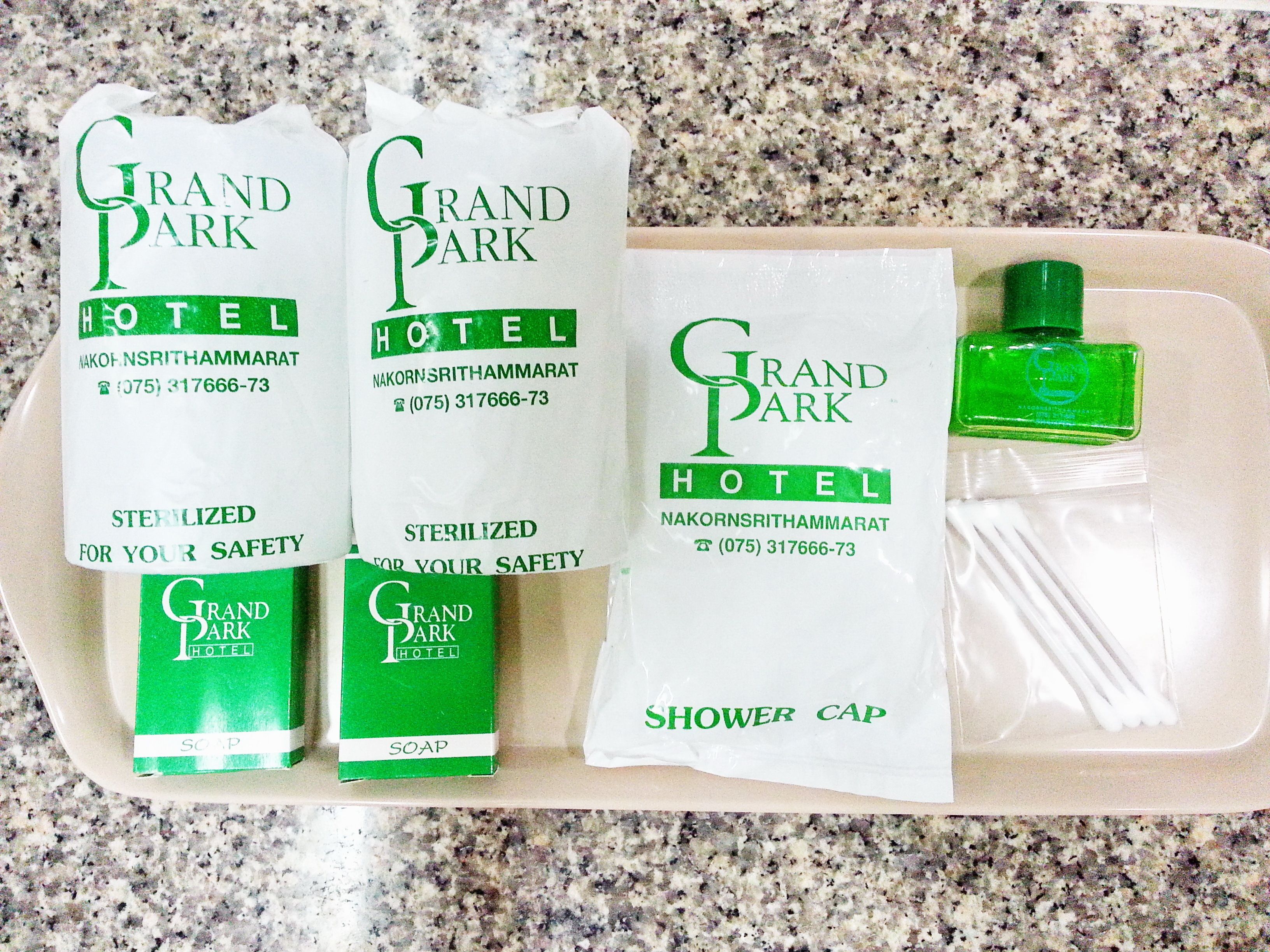 Three bottles of Grand Park Hotel soap, a shower cap, and a green bottle of shampoo.
