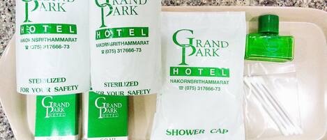 Three bottles of Grand Park Hotel soap, a shower cap, and a green bottle of shampoo.