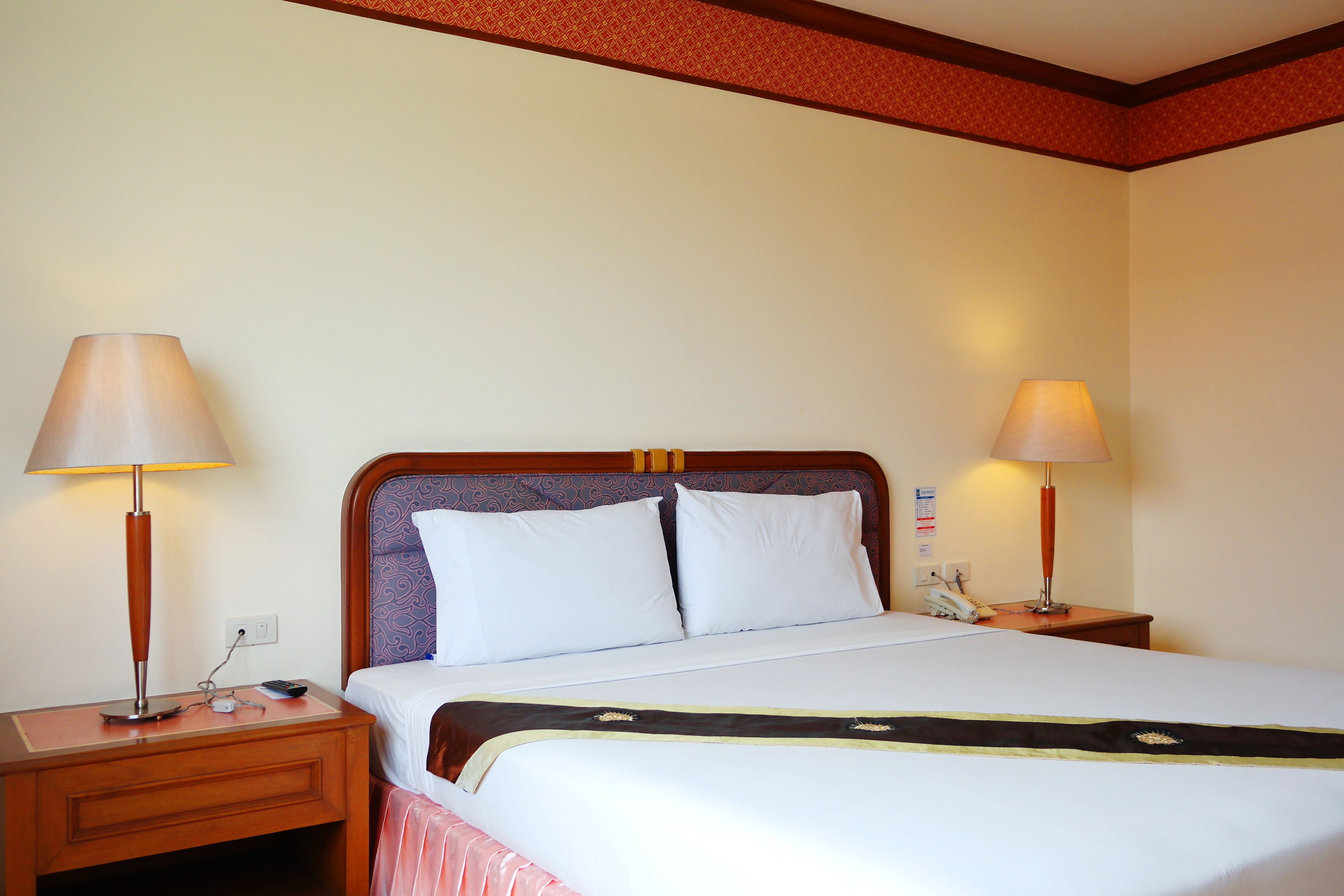 A hotel room with a bed, two bedside lamps, a nightstand, and a telephone.