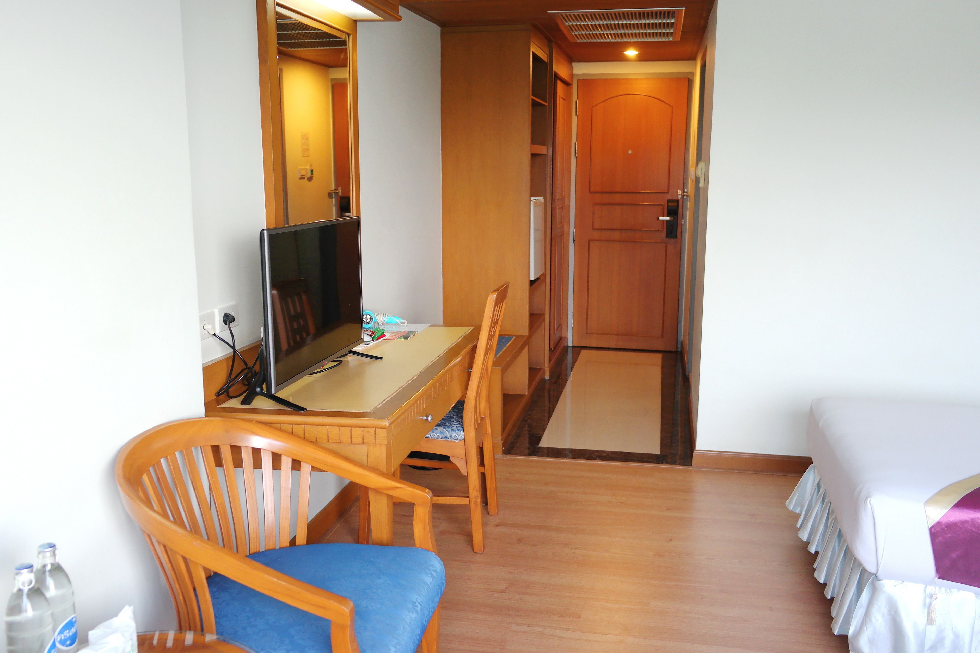 Une chambre d’hôtel avec un bureau en bois, une chaise, un lit et un téléviseur.