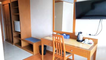 A compact room with a wooden desk, chair, and a television mounted on the wall.