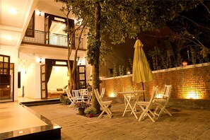An outdoor patio with a dining table and chairs, a yellow umbrella, and a brick wall. - Blue Lake Homestay (Da Nang)