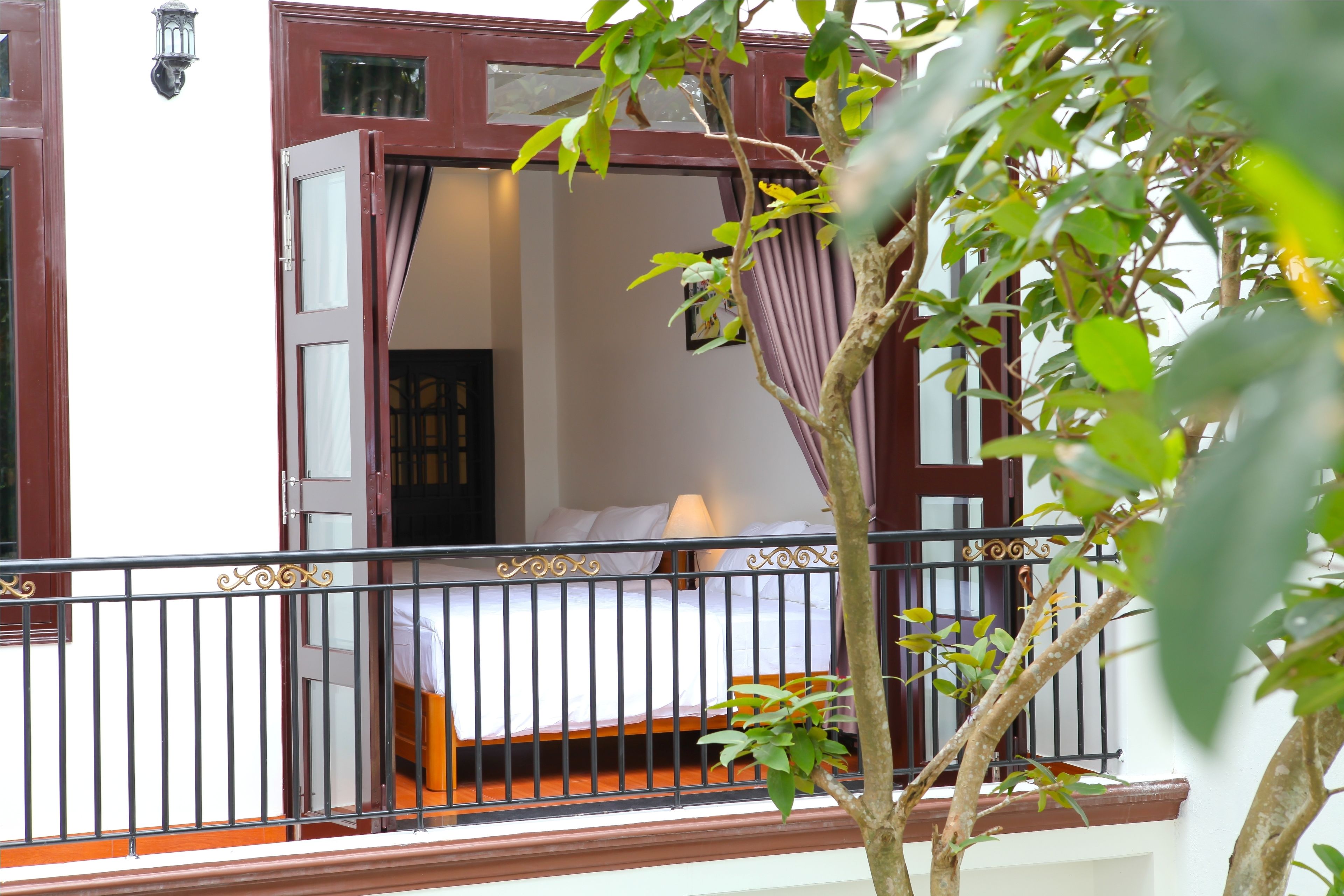 A hotel room with a bed, a window, and a balcony with a railing.
