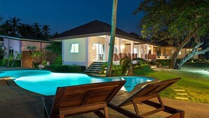 Una casa con piscina, sillas de descanso y una escalera que lleva al nivel superior.