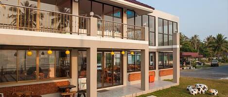 A two-story building with large windows, outdoor seating, and a balcony.