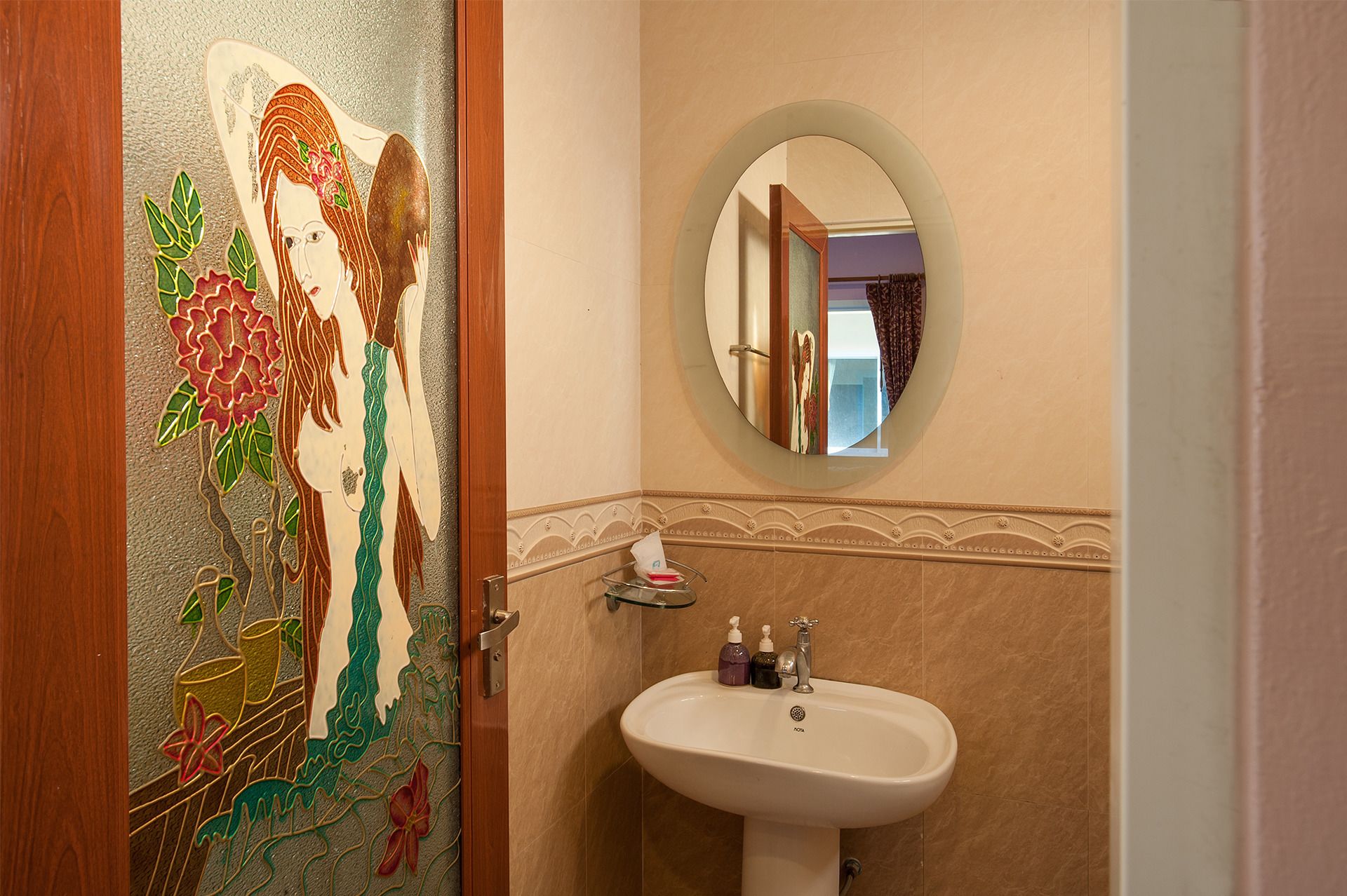 A bathroom with a decorative door, a sink, and a mirror.