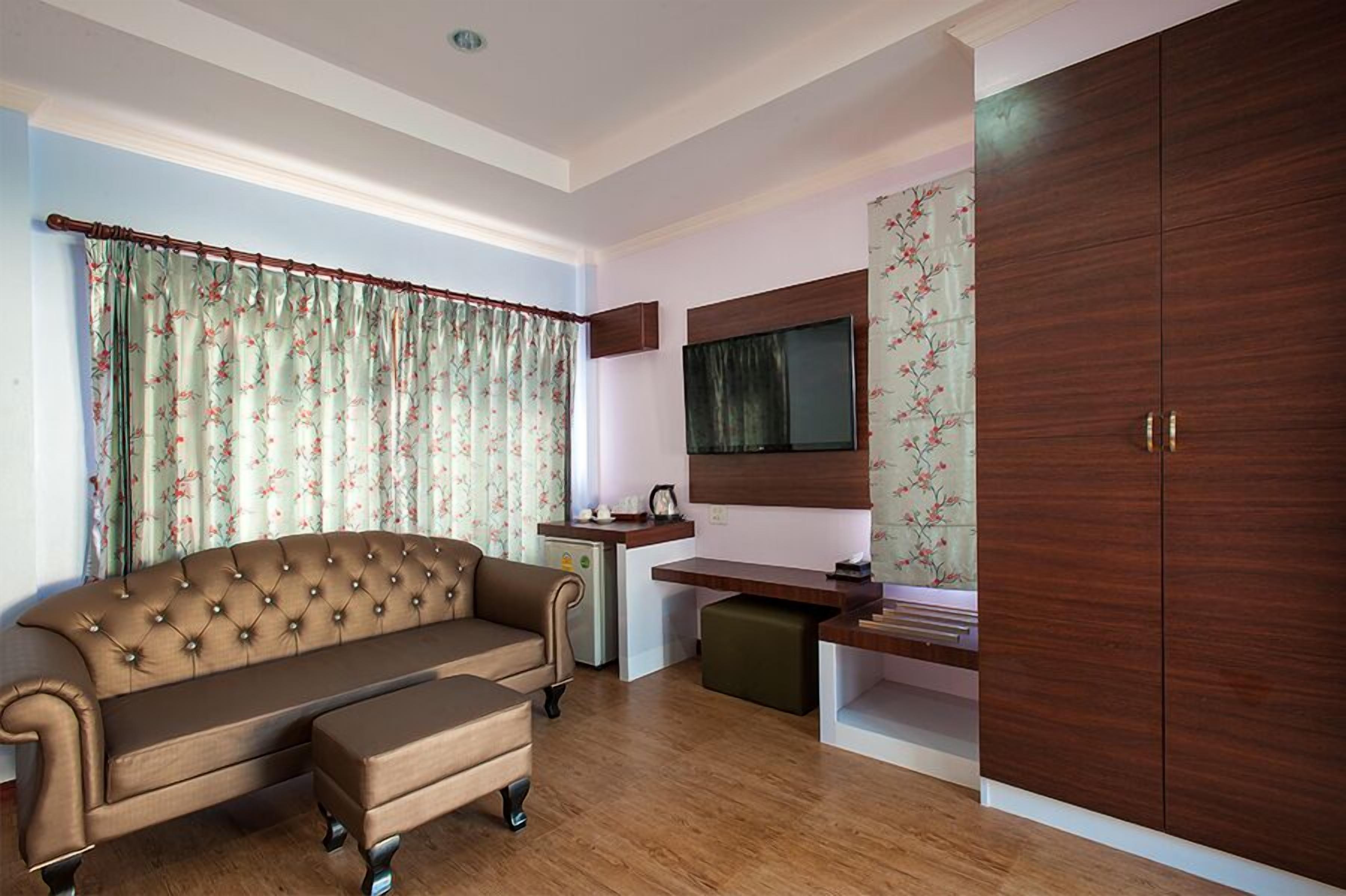 Un espacio habitable compacto con sofá, una kitchenette pequeña, un televisor montado en la pared y un armario.