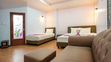 A hotel room with two single beds, a sofa, and a small table.
