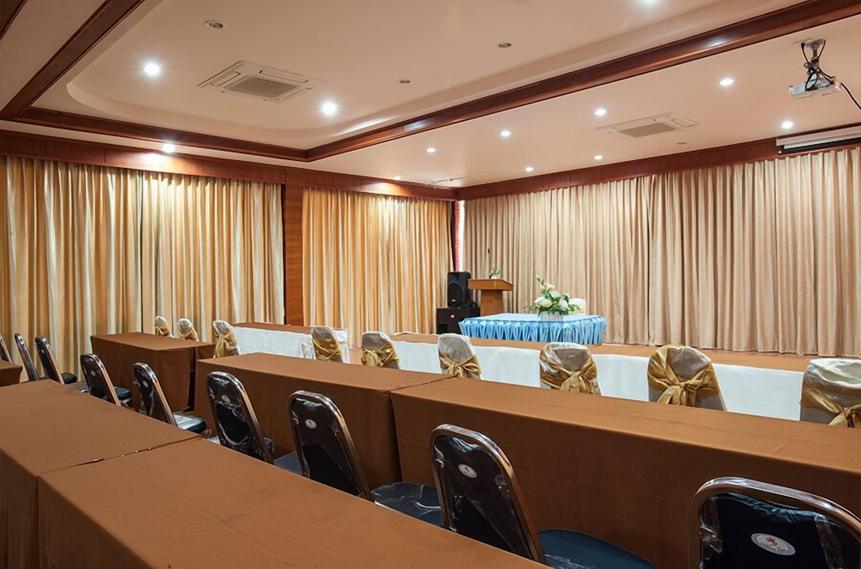 A conference room with a long table, chairs, a podium, and curtains.