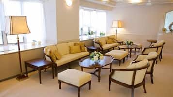 A well-lit living room with a sofa, ottoman, and multiple chairs arranged around a central coffee table.