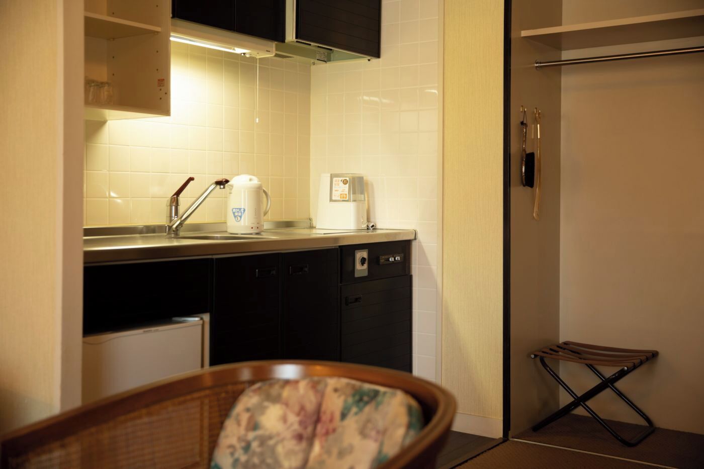 A compact kitchen with a sink, a kettle, a toaster, and a dishwasher.