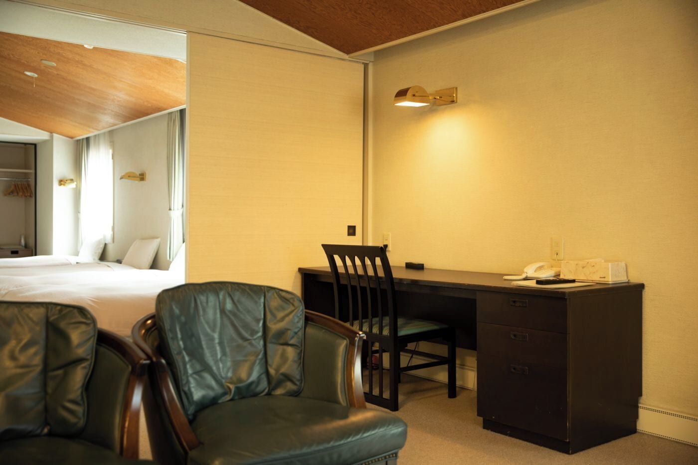 Una habitación de hotel con cama, escritorio con silla, teléfono y minibar.