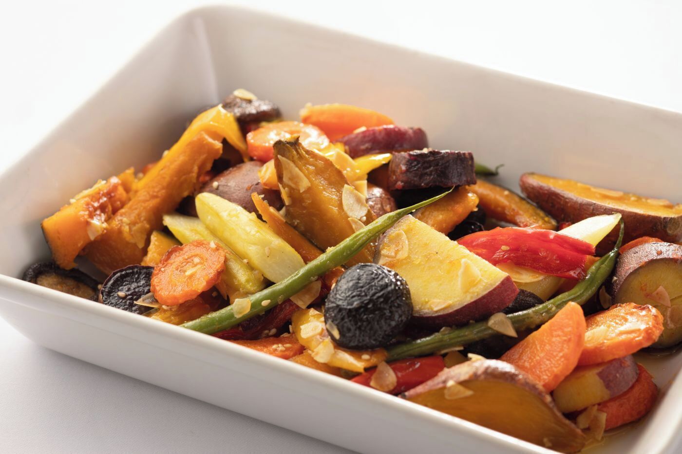 Un recipiente rectangular blanco con una variedad de verduras asadas.