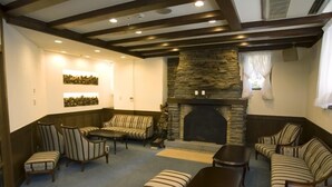 A cozy lounge area with a stone fireplace, striped sofas, and a coffee table. - Hotel Karuizawa Elegance (Karuizawa)