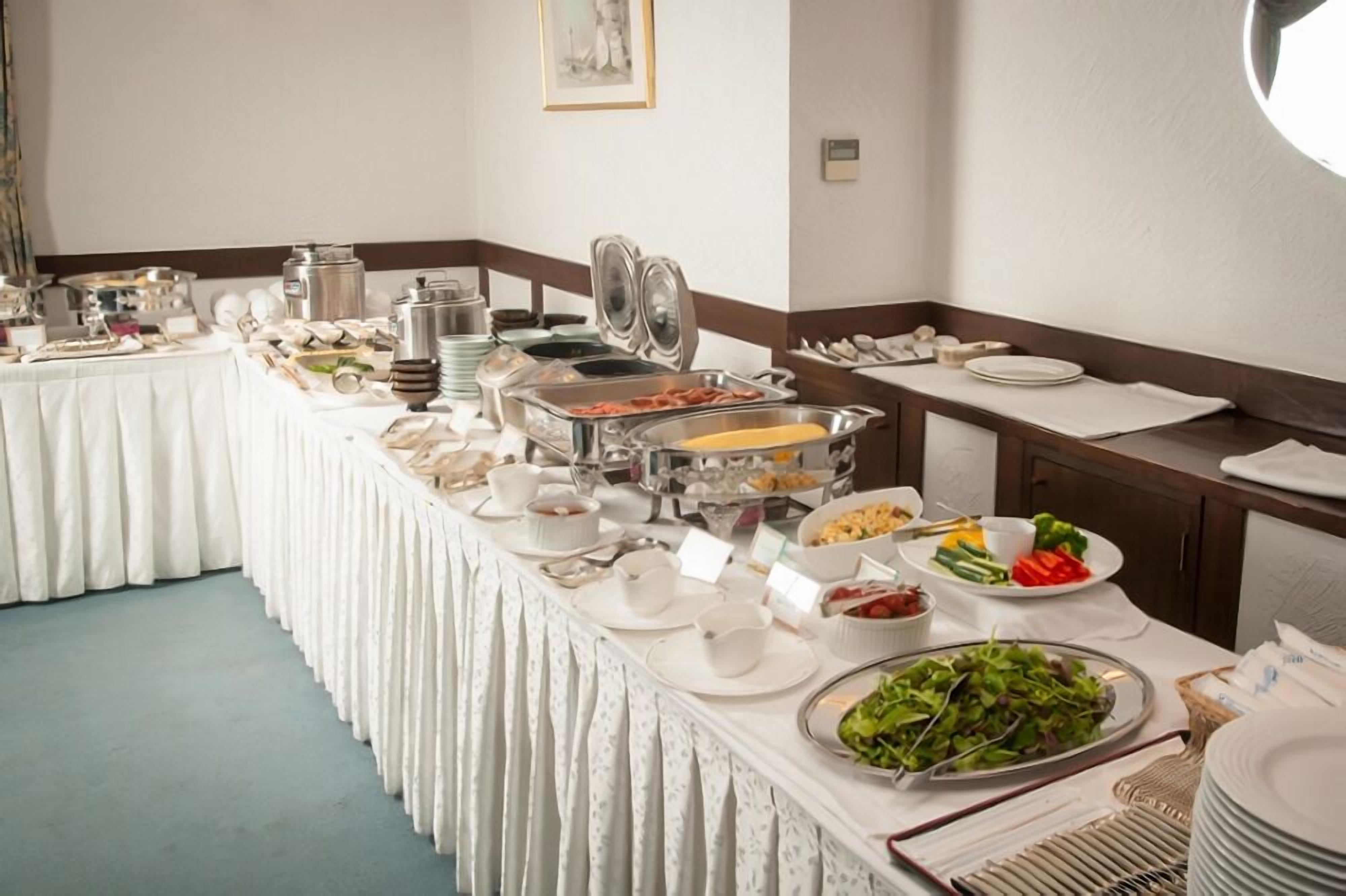 A buffet setup with various food items and serving utensils.