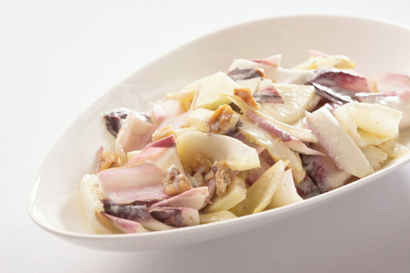 A white oval dish containing a salad with various ingredients.