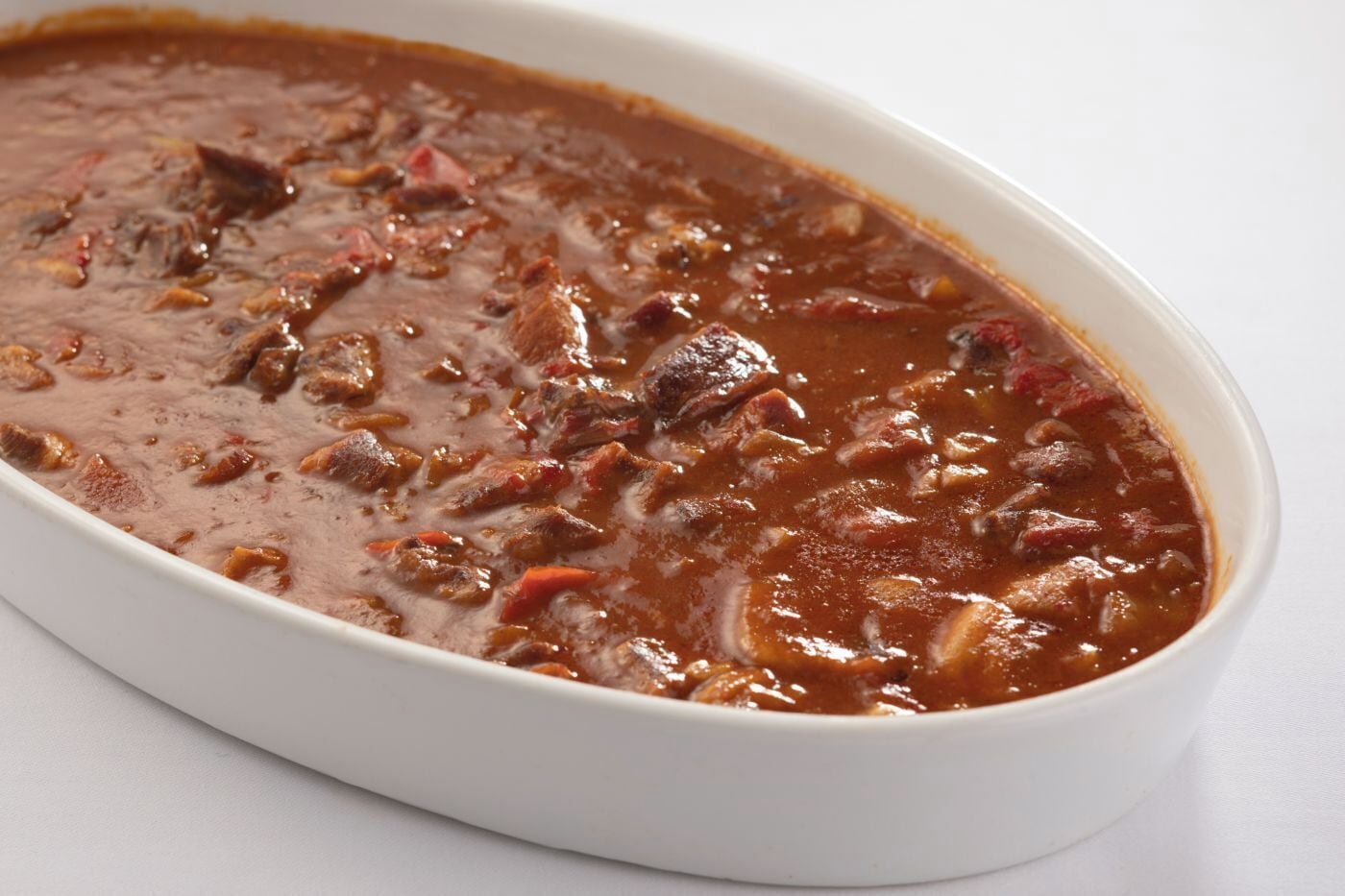 A white oval dish containing a stew with chunks of meat and vegetables.