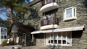 A stone building with a curved entrance, a balcony, and a window. - Hotel Karuizawa Elegance (Karuizawa)