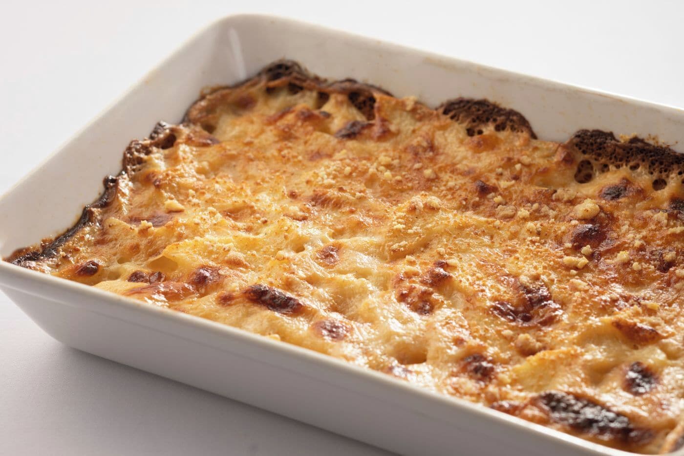 A rectangular white baking dish with a golden-brown baked dish, possibly a casserole or gratin, in a white interior.