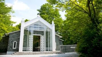 A small, white church with a stone facade, set in a lush green environment.