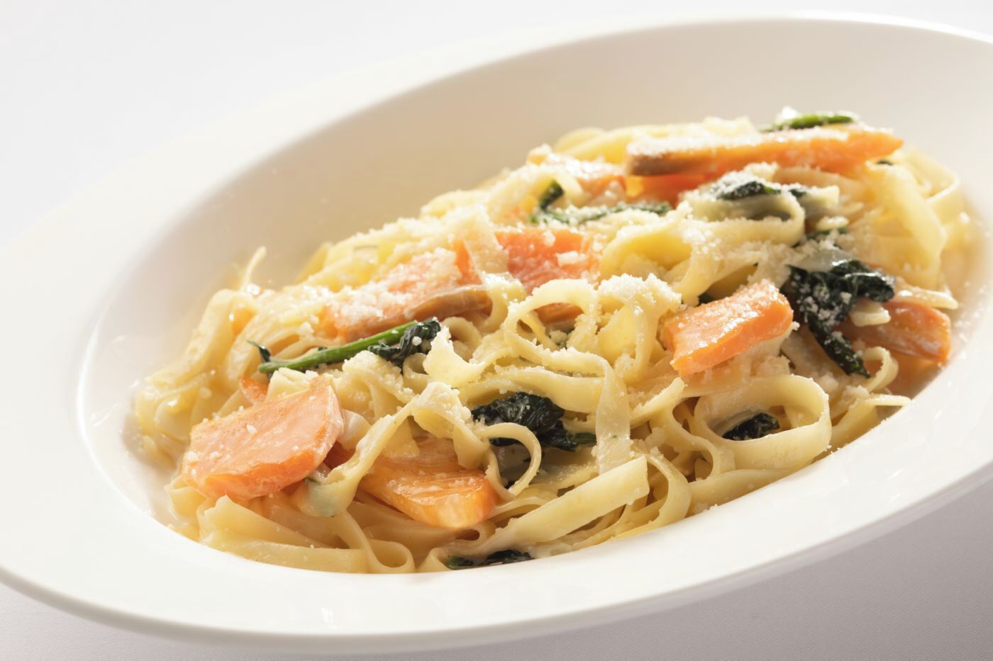 Eine Schüssel Pasta mit Karotten und Spinat.