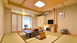 A traditional Japanese room with tatami flooring, a low table, a sofa, and sliding doors.