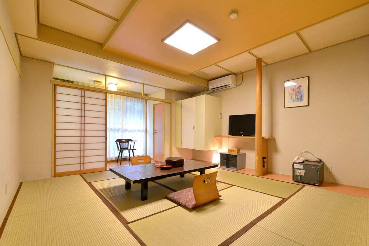 A traditional Japanese room with tatami flooring, a low table, a sofa, and sliding doors.