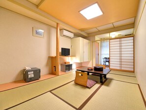 A traditional Japanese room with tatami flooring, a low table with cushions, a television, and a sliding door. - Shima Onsen Yuzurihaso Hot spring Inn (Nakanojo)
