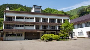 A multi-story building with a flat roof, large windows, and a parking area in front.