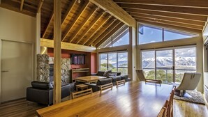 A spacious room with a large wooden table, comfortable seating, and a stone fireplace.