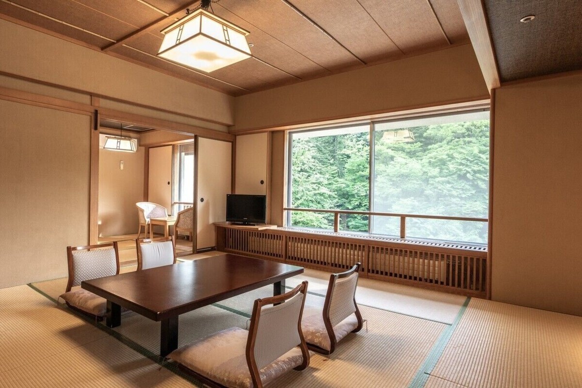 A traditional Japanese room with tatami flooring, a low table, and chairs.