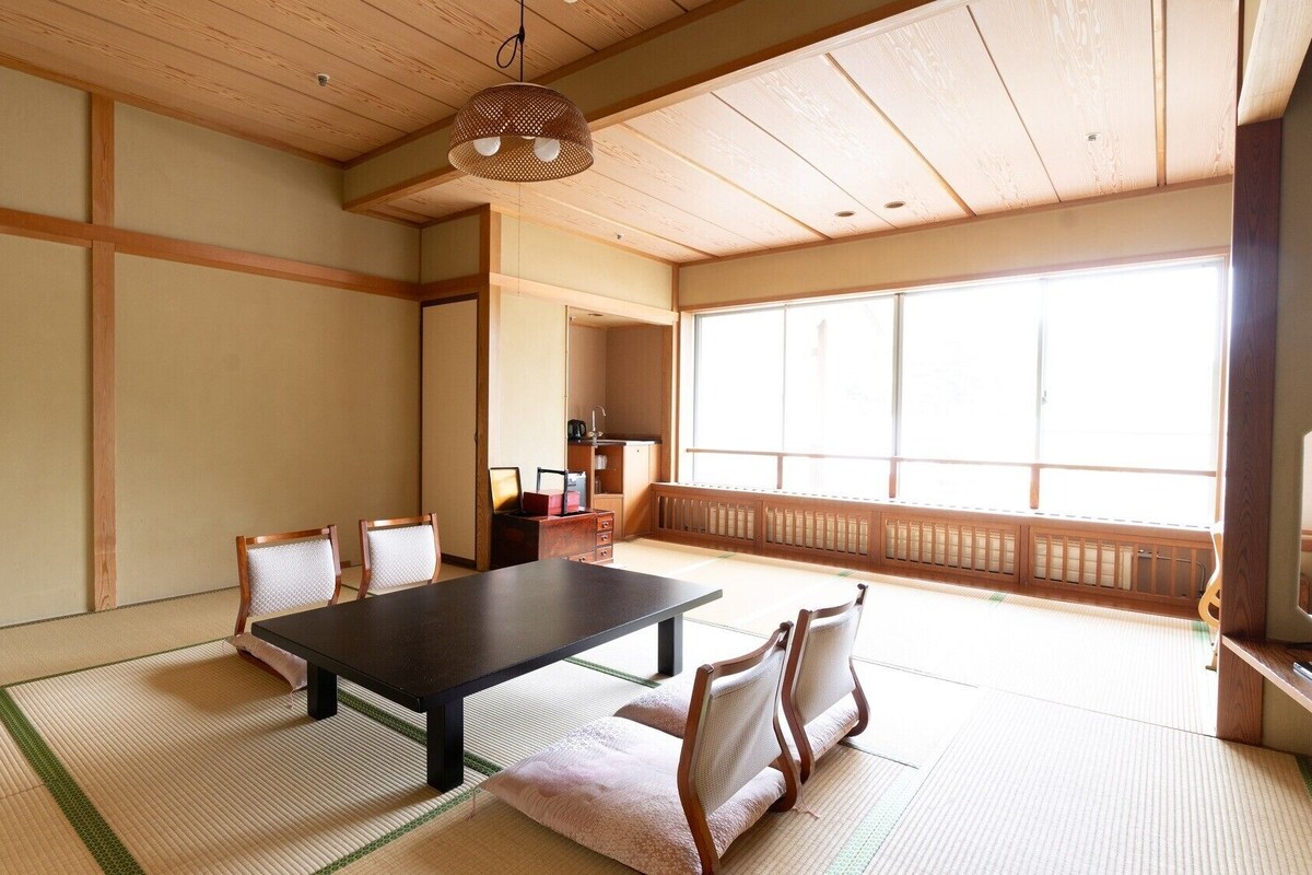 A traditional Japanese room with tatami flooring, a low table, and chairs.