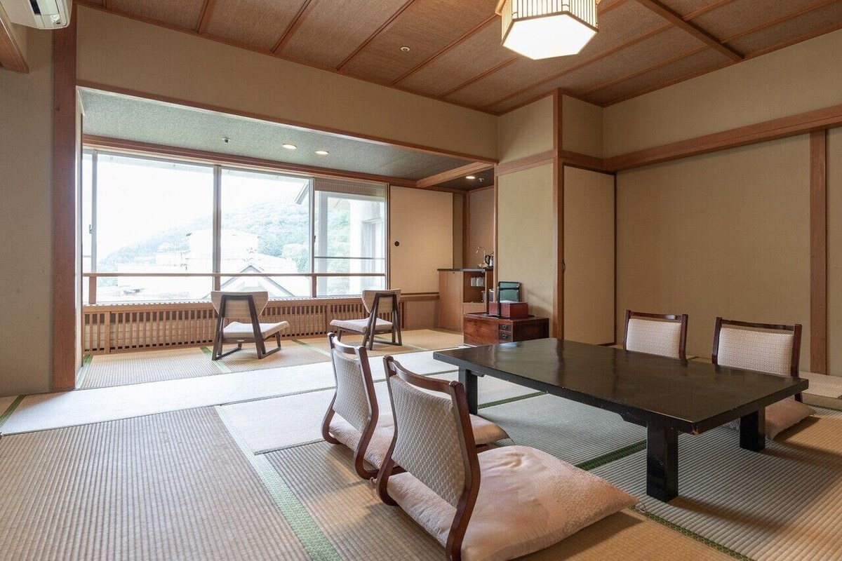 A traditional Japanese room with tatami flooring, a low table, and chairs.